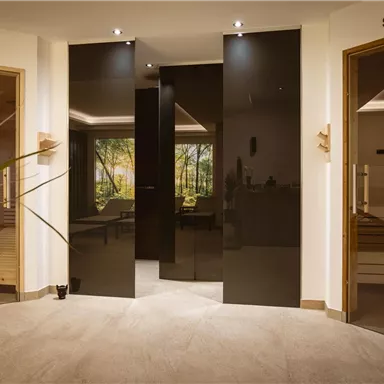 A modern wellness area with access to an infrared cabin and a sauna. The atmosphere is relaxing and welcoming, with warm light and plants.