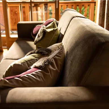 A modern sofa with colorful cushions in a bright room. Sunlight pours through the windows, creating a cozy atmosphere.