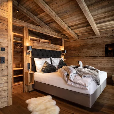 Ein gemütliches Schlafzimmer mit Holzwänden und einem großen Bett. Das Zimmer ist modern eingerichtet und strahlt Wärme aus.