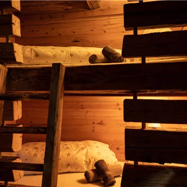 Ein gemütliches Schlafzimmer mit Etagenbetten aus Holz. Die warmen Lichter erzeugen eine einladende Atmosphäre.