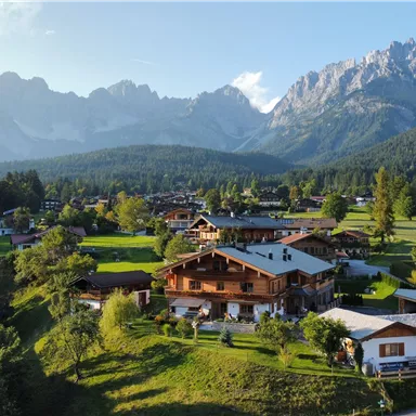 A picturesque mountain landscape with green meadows and traditional chalets. Majestic mountains can be seen in the background.