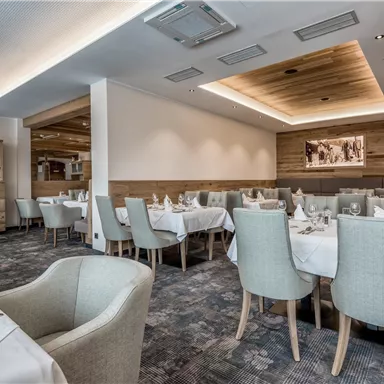 An elegant restaurant with bright tables and tasteful decor. The walls are made of wood and the lighting is soft and inviting.