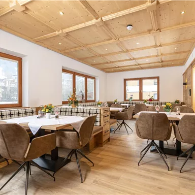 A cozy restaurant with wood paneling and modern furniture. The tables are decorated with flowers and offer an inviting atmosphere.