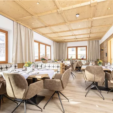 A modern restaurant with wooden ceilings and cozy seating. Large windows provide a view of the surroundings and ensure plenty of natural light.