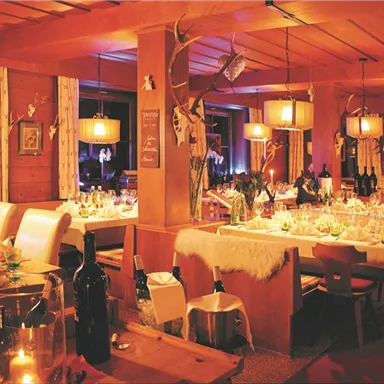 A cozy restaurant with wooden decor and warm lighting. Elegant tables are set, creating an inviting atmosphere.
