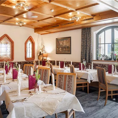 Ein einladendes Restaurant mit elegant gedeckten Tischen und einem gemütlichen Ambiente. Die Holzwände und Dekorationen verleihen einen traditionellen Charme.