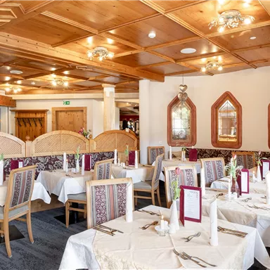Ein gemütliches Restaurant mit Tischen, die dekorativ eingedeckt sind. Der Holzdekor und die warmen Farben schaffen eine einladende Atmosphäre.