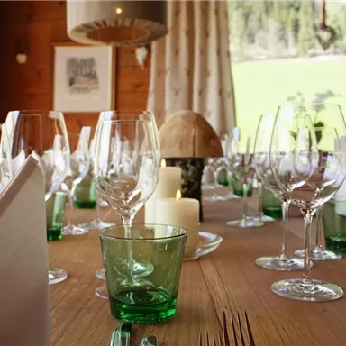 A beautifully set table with glasses and dishes in a cozy room. Natural light falls through the windows, creating an inviting atmosphere.