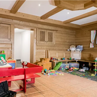 Ein einladendes Spielzimmer mit Holzverkleidung. Es gibt Spielzeug und Möbel in bunten Farben für Kinder.