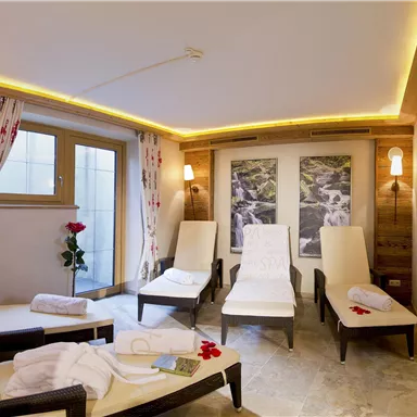 A relaxing wellness room with lounge chairs and soft lighting.
Lots of daylight comes through the windows and there are decorative elements like flowers.