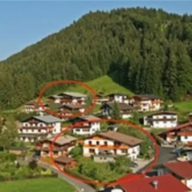 A picturesque mountain landscape with traditional houses and green meadows. The surroundings are surrounded by dense forests and offer a tranquil atmosphere.