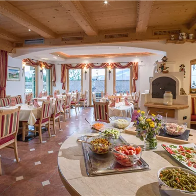 A cozy restaurant with wooden decor and tables covered with striped fabrics. On a table, various salads and fresh ingredients are arranged.