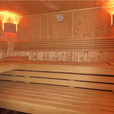 A cozy wooden sauna with warm light. The benches invite you to relax.