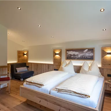 A cozy bedroom with two single beds and warm wooden furniture. The lighting creates an inviting atmosphere.