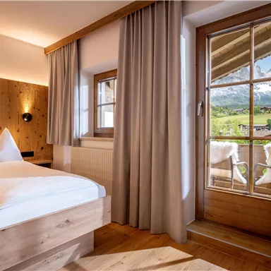 A cozy room with wooden paneling and a large window. Through the window, you can see the picturesque mountain landscape.