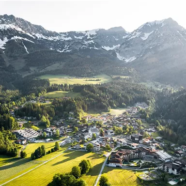 A picturesque alpine landscape with a small village in the valley. The snow-covered peaks and green meadows create an idyllic atmosphere.
