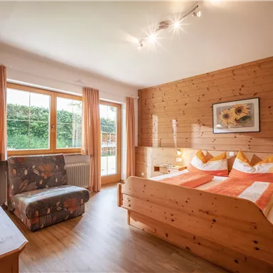 Ein gemütliches Schlafzimmer mit hölzernem Interieur. Das Zimmer ist hell und bietet ein Doppelbett sowie einen Fernseher.