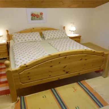 A cozy bedroom with a large wooden bed and comfortable pillows. Two nightstands with lamps and rugs create an inviting atmosphere.
