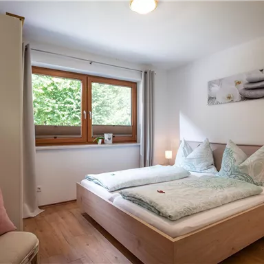 A modern bedroom with two beds, decorated in soft colors.
Large windows let in plenty of daylight and offer a view of nature.