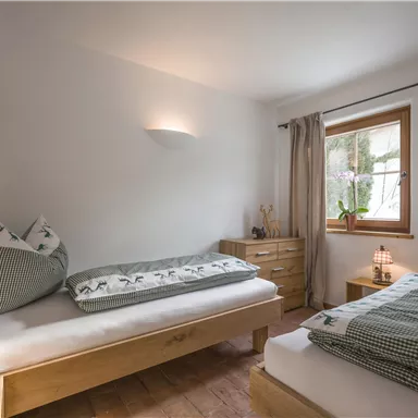 Ein gemütliches Schlafzimmer mit zwei Einzelbetten und natürlichem Licht. Die Einrichtung ist schlicht und modern, mit Holz- und Textilelementen.