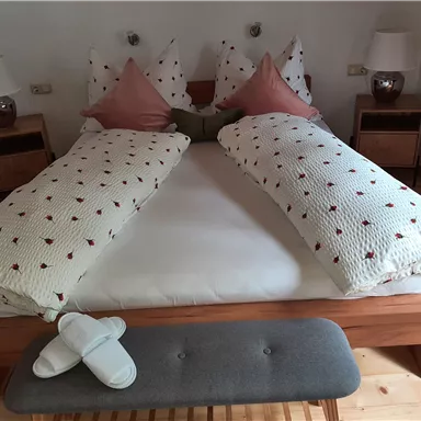 A cozy bedroom with a large bed and decorative pillows. Next to the bed are nightstands with lamps.
