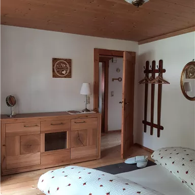 A cozy bedroom with wooden details and a double bed. There is a vanity table and a wardrobe on the wall.