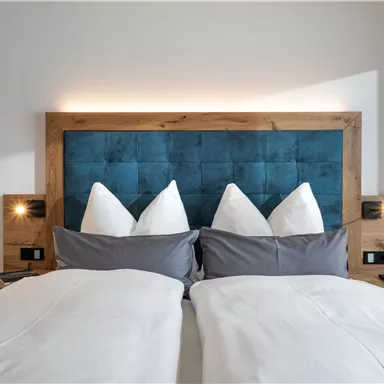 A cozy bedroom with a double bed and tasteful wall design. The pillows are carefully arranged, creating an inviting atmosphere.