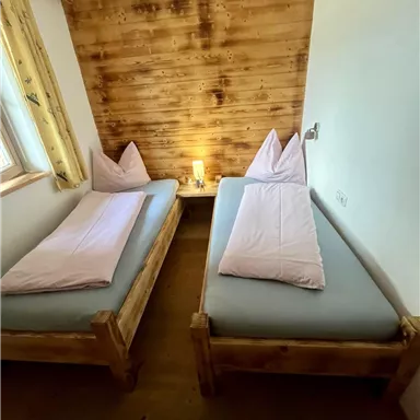A cozy room with two single beds and wooden paneling. The soft light creates a relaxed atmosphere.
