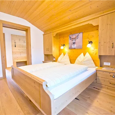 Ein gemütliches Schlafzimmer mit Holzvertäfelung und einem großen Bett. Die sanfte Beleuchtung sorgt für eine entspannte Atmosphäre.