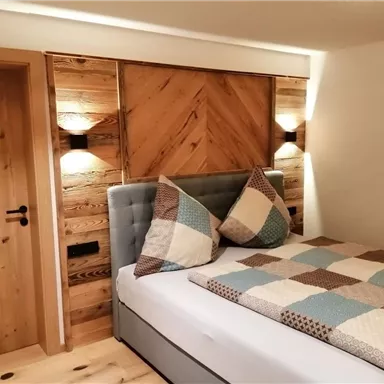 Ein modernes Schlafzimmer mit einem gemütlichen Bett und einer Holzwand. Die Dekoration ist schlicht und einladend.