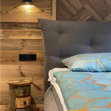 Ein gemütliches Schlafzimmer mit einem großen Bett und einer interessanten Holzwand. Neben dem Bett steht ein farbenfroher Nachttisch mit mehreren Schubladen.