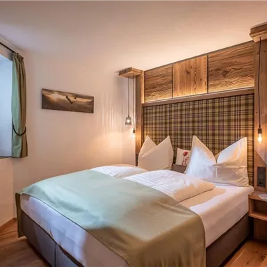 Ein gemütliches Schlafzimmer mit Holzverkleidung und einem großen Bett. Die warmen Farben und sanften Lampen sorgen für eine einladende Atmosphäre.