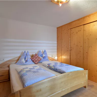 A cozy bedroom with a double bed and wood paneling. The walls are light, and there is a pleasant atmosphere.