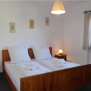 Ein gemütliches Schlafzimmer mit zwei Betten und natürlicher Holzverkleidung. Die Fenster lassen viel Licht herein und schaffen eine einladende Atmosphäre.
