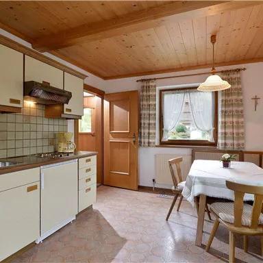 A cozy kitchen with wooden ceilings and a dining area. The decor is simple and inviting.