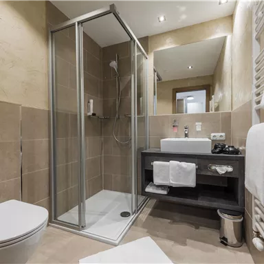 A modern bathroom with a shower, a sink, and a toilet. It is well-lit and has an elegant, neutral color scheme.