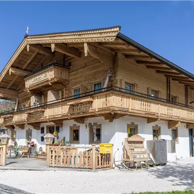 A traditional Alpine wooden house with several balconies. Surrounded by a clear blue sky and a beautiful environment.