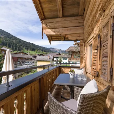 A cozy balcony with wooden cladding and a view of a picturesque mountain landscape. A decoration is on the table, perfect for relaxed hours outdoors.