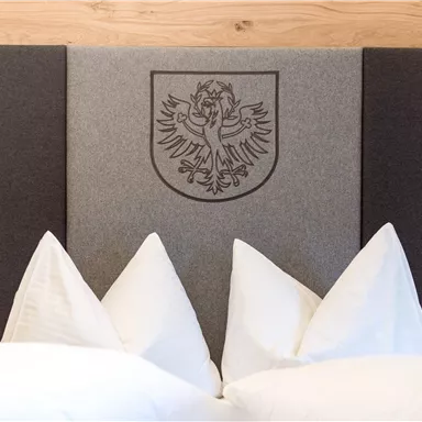 An elegant headboard with a crest and decorative pillows. The color scheme is simple and modern.