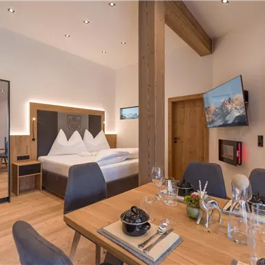A stylish room with a large bed and modern furniture. The dining area is elegantly decorated and accommodates several people.