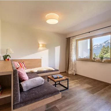A bright living room with modern design and a comfortable sofa. Large windows offer a view of the mountains.