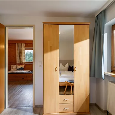 A cozy room with a wooden wardrobe and two windows. The room has a bright floor and is well lit.