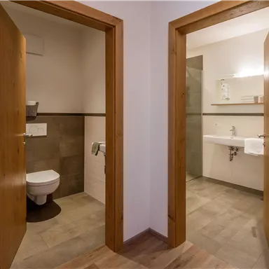 Two bathrooms with modern amenities. The left side has a toilet and the right side has a shower with a sink.