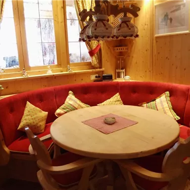 Ein gemütlicher Essbereich mit einem runden Tisch und einer roten Sitzbank. Das Holzinterieur schafft eine warme und einladende Atmosphäre.