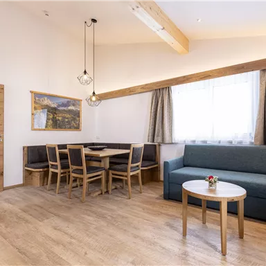 A modern living room with a comfortable sofa and a dining table. Large windows provide plenty of daylight and a cozy atmosphere.