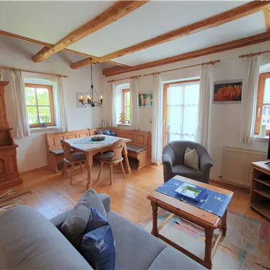 An inviting living room with wood-paneled walls and a large dining table. Bright windows create a friendly atmosphere.