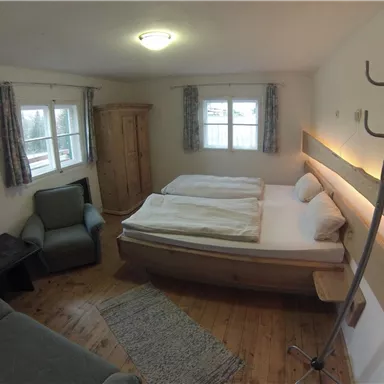 Ein gemütliches Schlafzimmer mit zwei Betten und einem kleinen Wohnbereich. Es gibt Fenster, die für viel natürliches Licht sorgen.