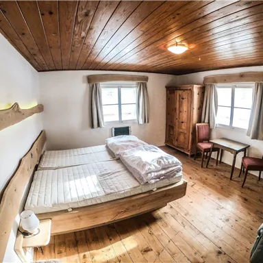 Ein gemütliches Schlafzimmer mit Holzdecke und einem großen Bett. Es gibt einen Tisch, zwei Stühle und einen Schrank.