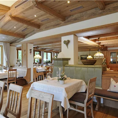A cozy restaurant with wooden furniture and warm lighting. The tables are set for guests and provide an inviting atmosphere.