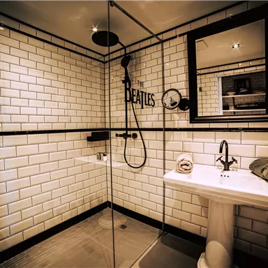A modern bathroom with white subway tiles and an elegant shower. A mirror and a sink complement the simple, stylish decor.